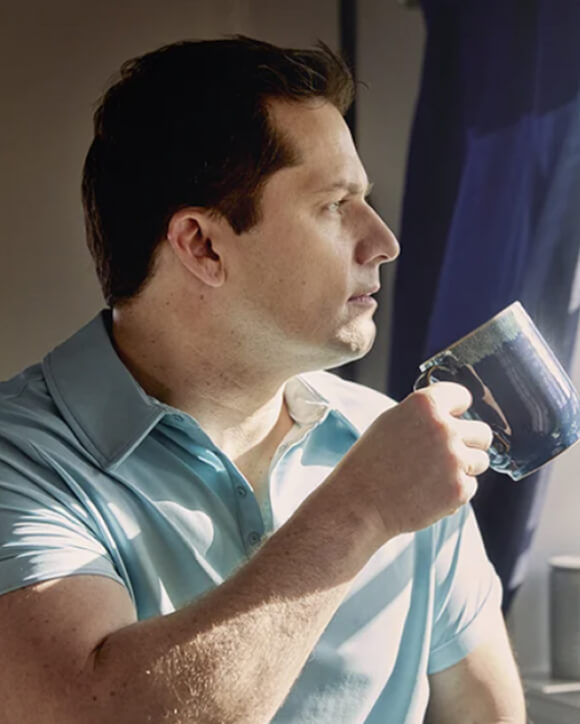 Ein Eversense CGM Benutzer hält einen blaue Tasse und trägt den Eversense Transmitter am Arm.