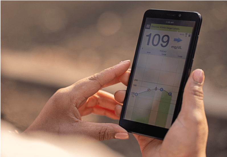 Hände halten ein Smartphone, auf dem die Eversense App zur Glukoseüberwachung 109 mg/dL anzeigt.