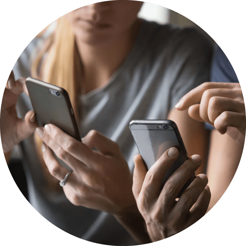 Zwei Eversense Benutzerinnen mit Smartphones, eine zeigt auf den Bildschirm und erklärt die Daten des CGM-Geräts.