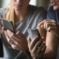 Zwei Eversense Benutzerinnen mit Smartphones, eine zeigt auf den Bildschirm und erklärt die Daten des CGM-Geräts.